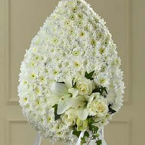 White funeral spray with lilies and roses on an easel