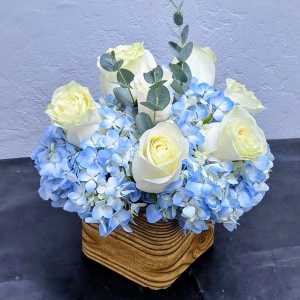 White roses and blue hydrangeas in a wooden basket