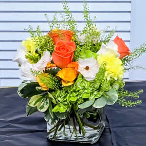 Bouquet of orange, white, and yellow roses in a clear vase