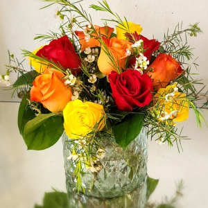 Bouquet of red, orange, and yellow roses in a clear glass vase
