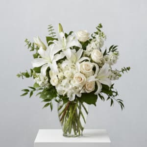 White lilies and roses arranged in a clear glass vase