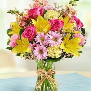 Bouquet of pink and yellow flowers in a clear glass vase
