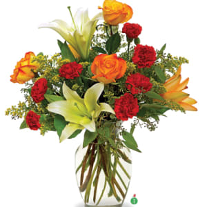 Bouquet of orange roses, red carnations, and white lilies in a clear glass vase