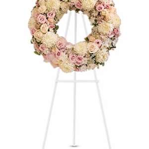 Standing wreath of white and pale pink flowers on a white metal easel