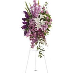 Tall purple and lavender standing spray with white lilies on a white easel.