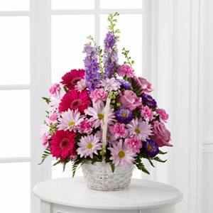 Pink and purple mixed flower arrangement in a white basket