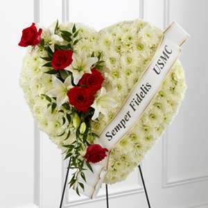 Heart-shaped funeral wreath with red roses and white lilies on a stand