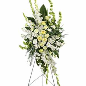Tall white and pale yellow funeral spray on a metal easel