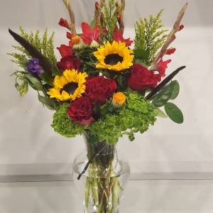 Mixed bouquet of sunflowers and red roses in a clear glass vase