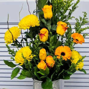 Yellow chrysanthemums and orange roses in a silver vase