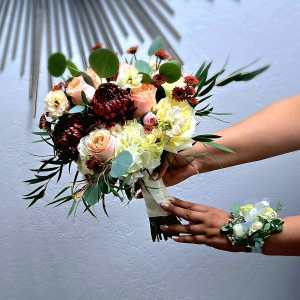 Handheld bouquet of roses, hydrangeas, and dark mums with greenery
