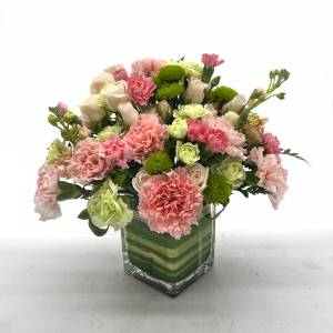 Pink and green floral arrangement in a square glass vase