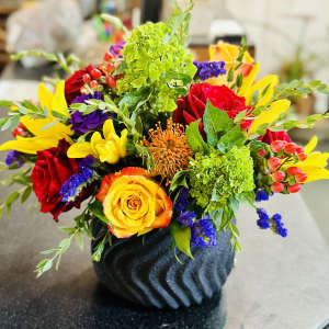 Colorful mixed flower arrangement in a dark textured vase