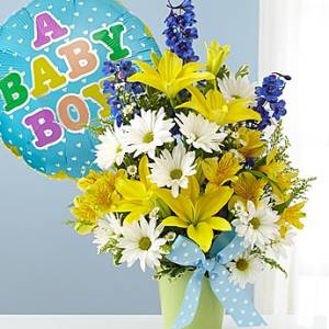 Bouquet of yellow lilies and white daisies in a green vase with a baby balloon