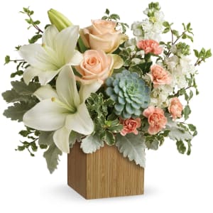 White lilies, peach roses, and pink carnations in a wooden cube vase