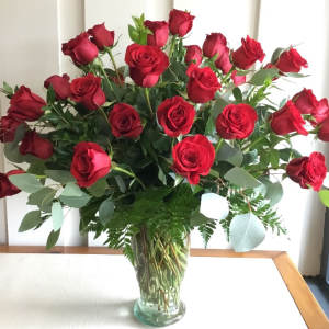 A large bouquet of red roses in a clear glass vase