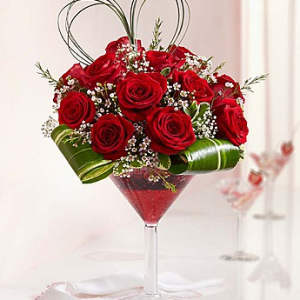 Red roses arranged in a martini glass with baby's breath