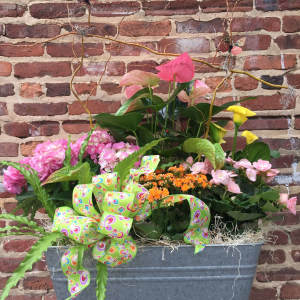 Mixed floral planter with pink hydrangeas, anthuriums, and yellow calla lilies in a metal container