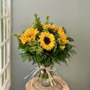 Sunflower bouquet in a clear glass vase with a raffia bow