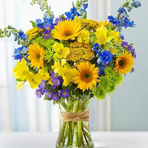 Bouquet of yellow and blue flowers in a clear glass vase