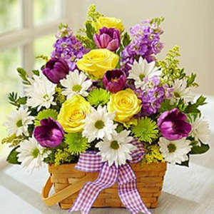 Basket arrangement of yellow roses, purple tulips, and white daisies