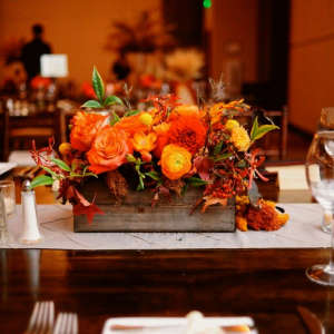 Orange floral centerpiece in a wooden box on a banquet table