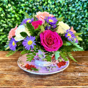 Bouquet of pink and white roses with purple daisy-like flowers in a floral teacup