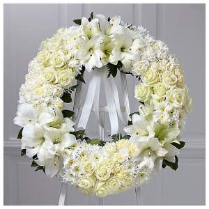 White floral wreath with roses and lilies on a stand