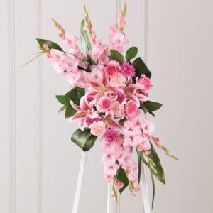 Pink floral standing arrangement with lilies and roses on a white easel