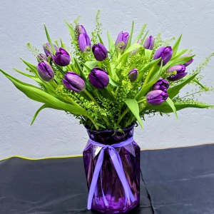 Purple tulips arranged in a purple vase with a ribbon