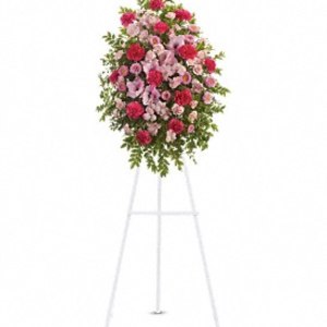 Oval standing spray of pink and red flowers on a white metal easel