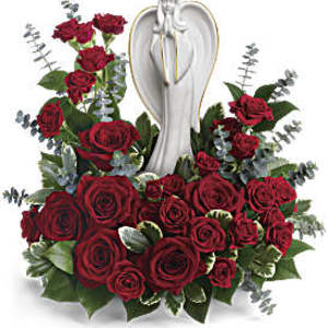 Low arrangement of red roses surrounding a white angel figurine
