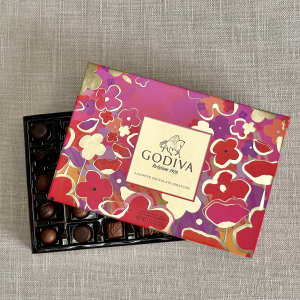 Box of assorted chocolates with a colorful floral lid