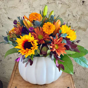 Mixed bouquet in a white pumpkin vase with sunflowers, mums, and lilies