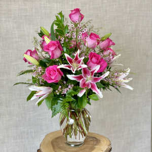 Pink roses and lilies arranged in a clear glass vase