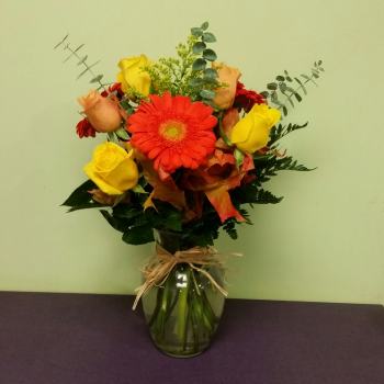 Bouquet of red gerbera daisies and yellow roses in a glass vase
