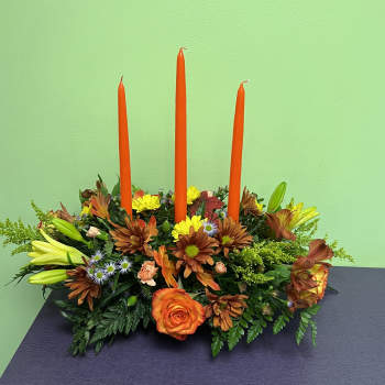Orange candle centerpiece with mixed flowers and lilies