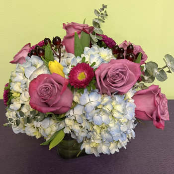 Pink roses and blue-white hydrangeas in a low vase arrangement