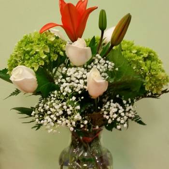 Bouquet of lilies, roses, hydrangeas, and baby's breath in a glass vase