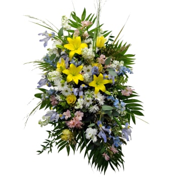 Large standing floral spray with yellow lilies, white daisies, and pastel blooms