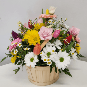 Mixed bouquet of daisies, tulips, and roses in a wooden basket