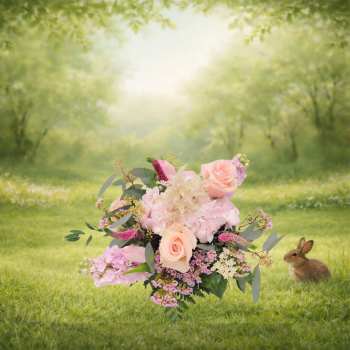 Pink and peach floral bouquet with a rabbit in a grassy field