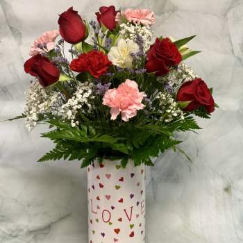Bouquet of red roses and pink carnations in a heart-patterned vase