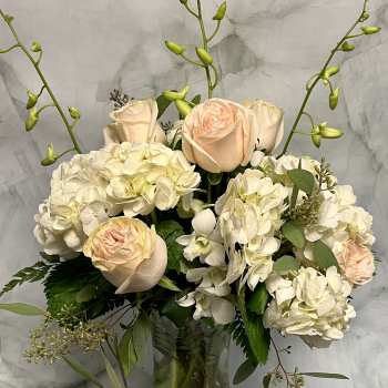 Cream and blush roses with white hydrangeas in a glass vase