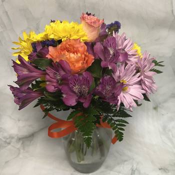 Colorful bouquet of roses, alstroemeria, and daisies in a glass vase