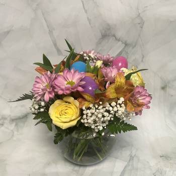 Mixed bouquet of pink daisies, yellow rose, and alstroemeria in a glass vase