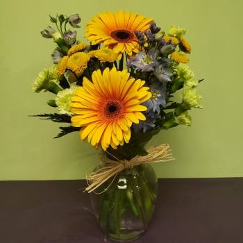 Bouquet of yellow gerbera daisies and mixed blooms in a glass vase