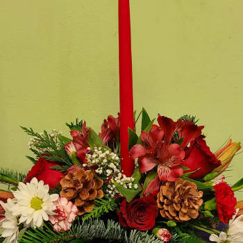 Red candle in a floral arrangement with roses, daisies, and pinecones