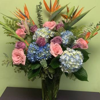Bouquet of pink and purple roses with blue hydrangeas in a glass vase