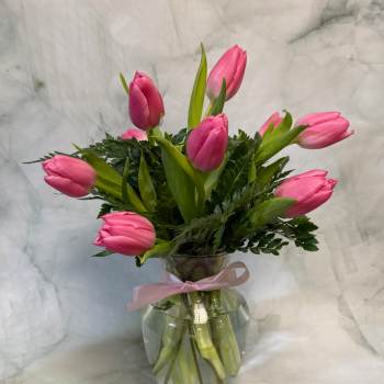 Pink tulip bouquet in a clear glass vase with a pink ribbon